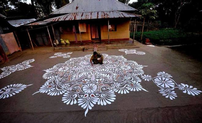 Village woman in Bengal decorating her simple courtyard with Alpana.