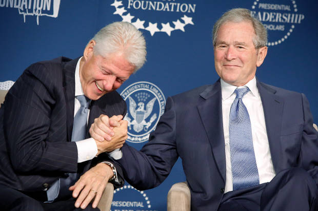 Former U.S. presidents Bill Clinton and George W. Bush shake hands and joke on stage during a Presidential Leadership Scholars program event at the Newseum in Washington
